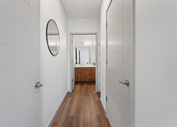 a hallway with white walls and wooden floors and a mirror