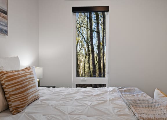 a bedroom with a bed and a window with trees