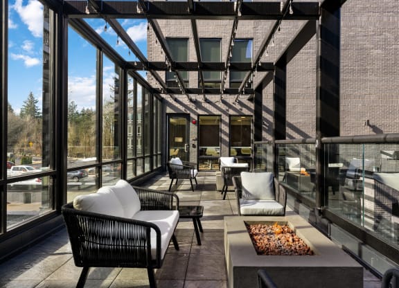 a patio with chairs and a coffee table and large windows