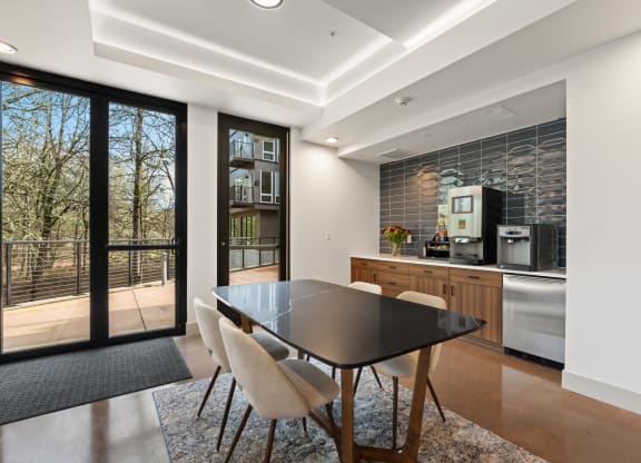 a dining room with a black table and chairs and a kitchen with glass doors