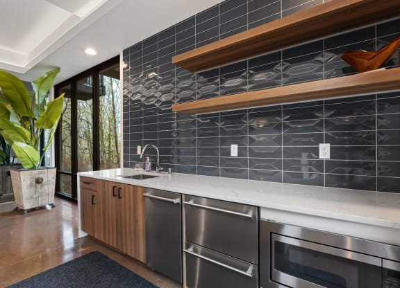 a kitchen with stainless steel appliances and a black tile backsplash