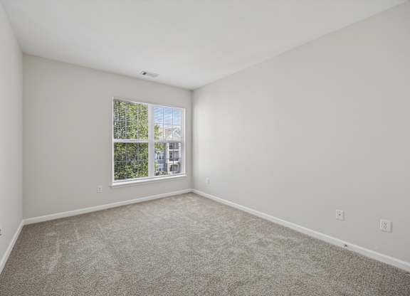A room with a window and carpeted floor.