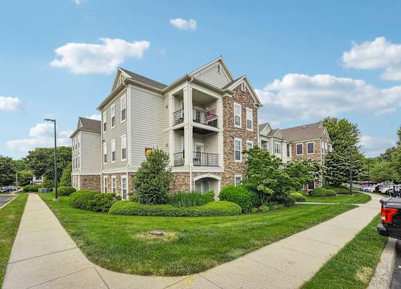 A large apartment building with a grassy front yard and a sidewalk.