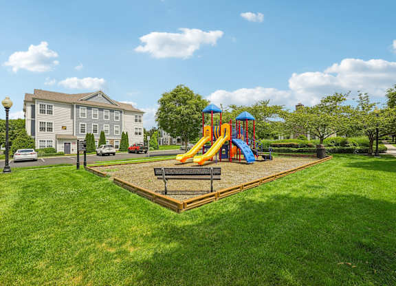 A playground with a slide and a wooden platform in the middle of a grassy area.