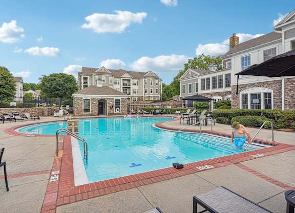 A man is sitting on the edge of a swimming pool.