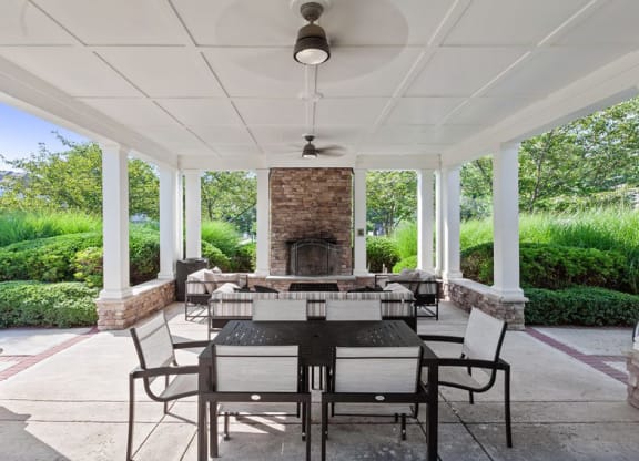 a covered patio with a fireplace and a dining table and chairs  at Harper's Crossing, Langhorne, PA, 19047