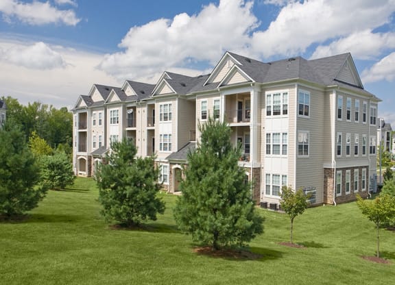 a large apartment building on a sunny day with trees in front of it  at Harper's Crossing, Pennsylvania