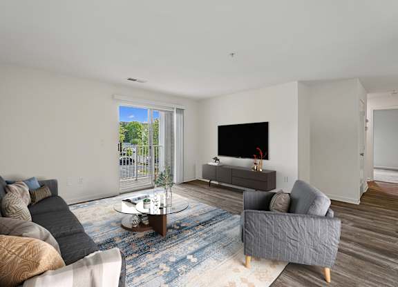 A living room with a grey couch, a coffee table, and a flat screen TV.