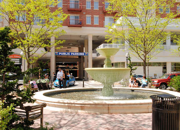 A fountain in the middle of a plaza with a sign that says