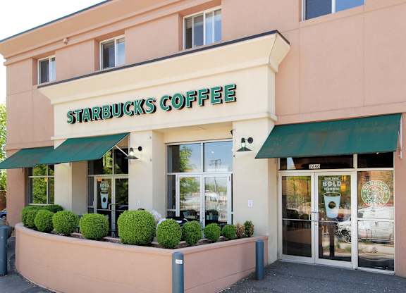 A Starbucks Coffee store with green awnings and a pink building.