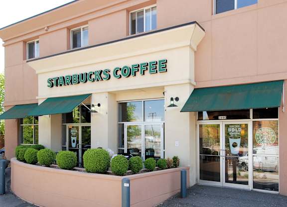 A Starbucks Coffee store with green awnings and a pink building.