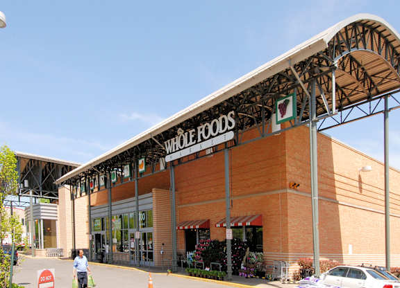 A storefront of a Whole Foods store with a person walking in front.
