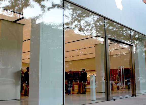 A glass facade of a building with the Apple logo on it.