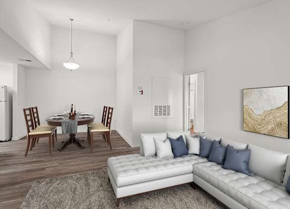 A modern living room with a white couch and a dining table set up.