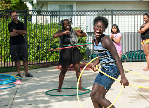 A woman is playing with a hula hoop in a driveway.
