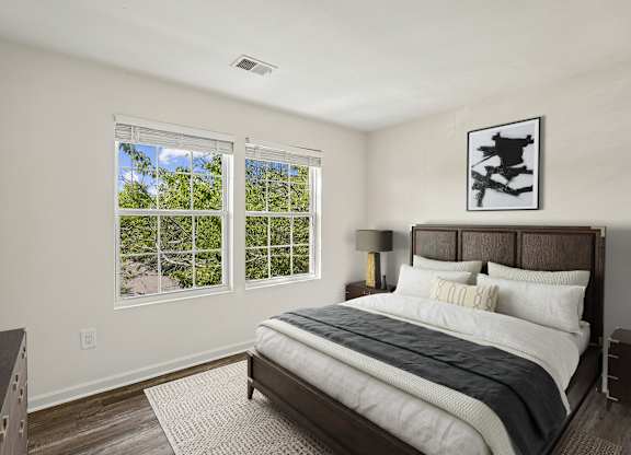 A bedroom with a large bed and a window overlooking a tree-filled landscape.