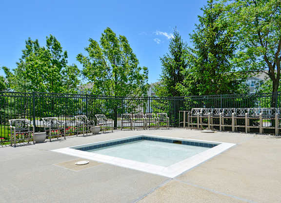 A small pool surrounded by a fence and trees.