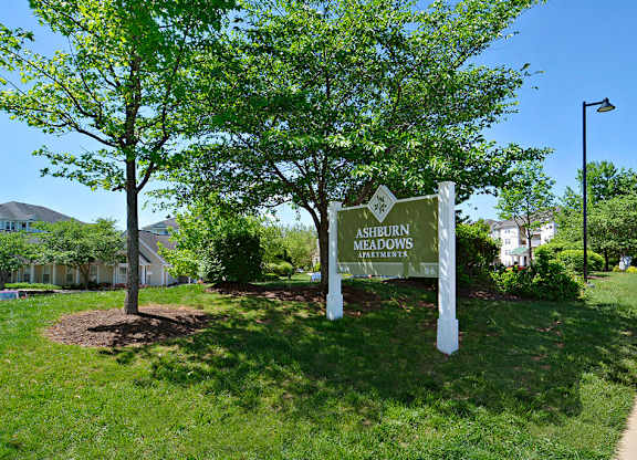 A sign for Ashdown Apartments stands in a grassy area.
