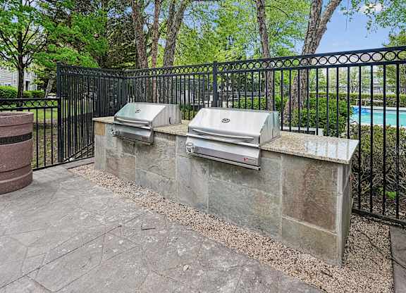 A black metal fence surrounds a stone wall with two mailboxes on it.