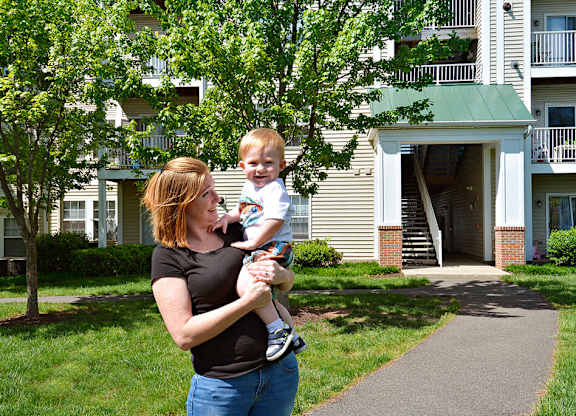 A woman holding a baby in front of a building.