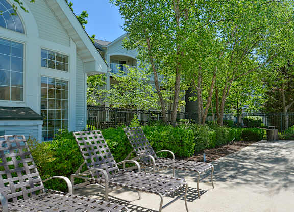 A patio with chairs and a table in front of a house.