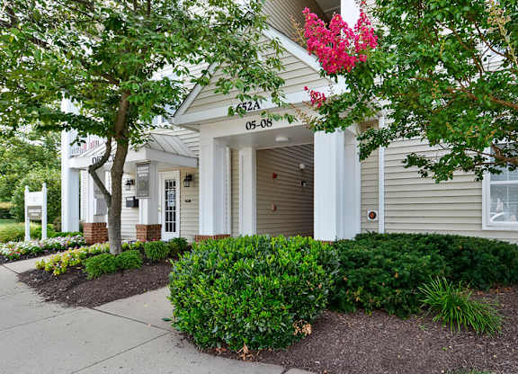 A house with a tree and bushes in front.