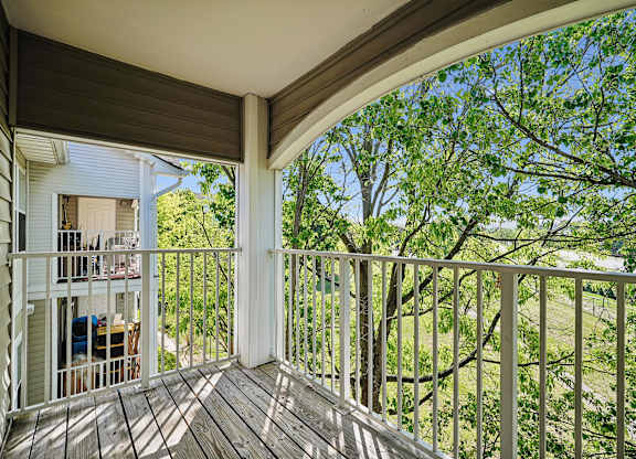 A balcony with a white railing and a view of trees.