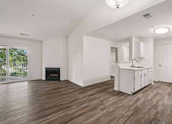 A large, empty room with wood flooring and white walls.