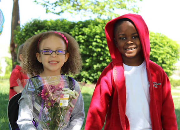 A young girl with glasses is holding a bouquet of flowers.