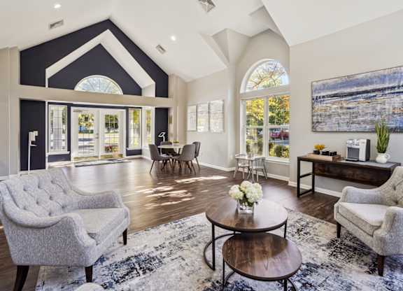 A living room with a grey sofa, a grey armchair, a wooden coffee table, and a large painting on the wall.