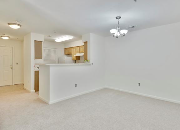 A large, empty room with a kitchenette in the background.