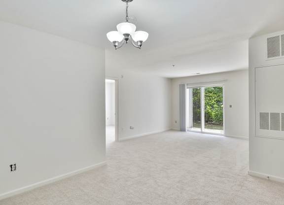 A spacious, empty room with a chandelier and a window.