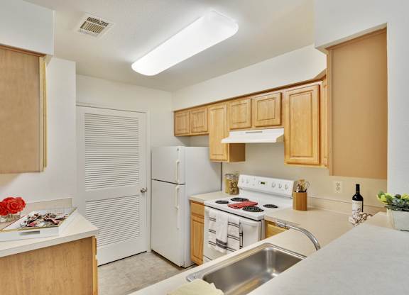 A kitchen with white appliances and wooden cabinets.
