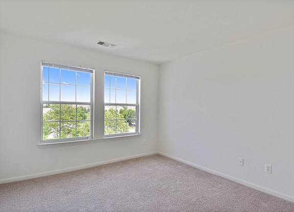 A room with two windows and carpeted floor.