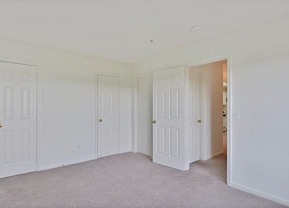 A room with white doors and carpeted floor.