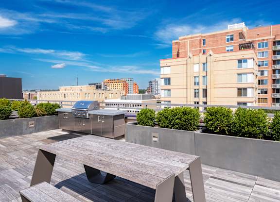 A modern outdoor seating area with a large table and chairs overlooking a cityscape.
