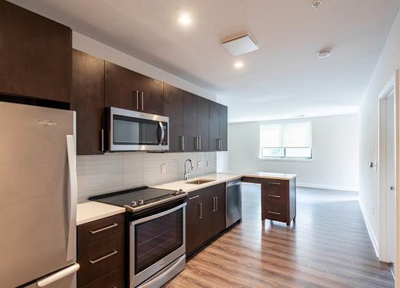 A modern kitchen with dark wood cabinets and stainless steel appliances.
