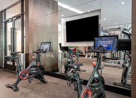A gym with stationary bikes and a TV screen.
