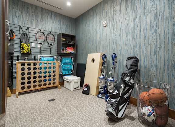 A room with a wooden floor and a blue wall with a basket of balls and a pair of shoes.