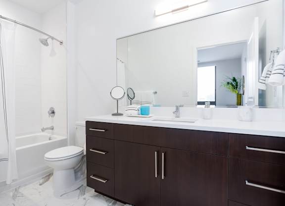A white bathroom with a toilet, sink, and mirror.