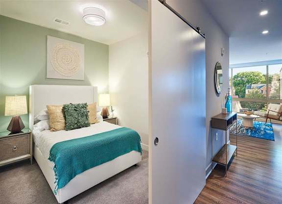 A bedroom with a bed, nightstand, and a mirror on the wall.