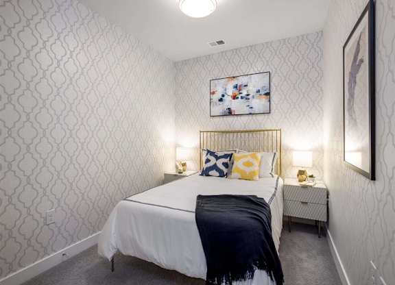 A bedroom with a white bed and a patterned wallpaper.