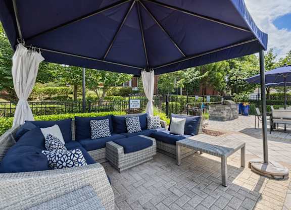 a patio with couches and umbrellas and tables at Tradition at Stonewater, North Carolina