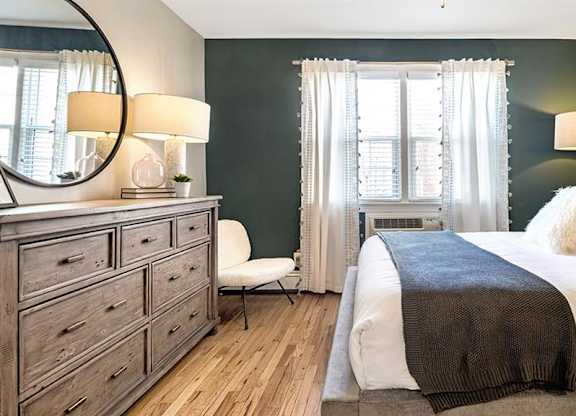 Large bedroom featuring queen size bed, full size dresser, and accent chair at Alister Morristown, Morristown, NJ, 07960