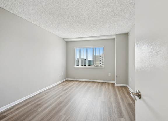 A room with a window and wooden flooring.