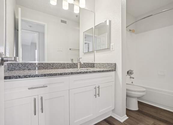 A bathroom with a toilet, sink, and mirror.