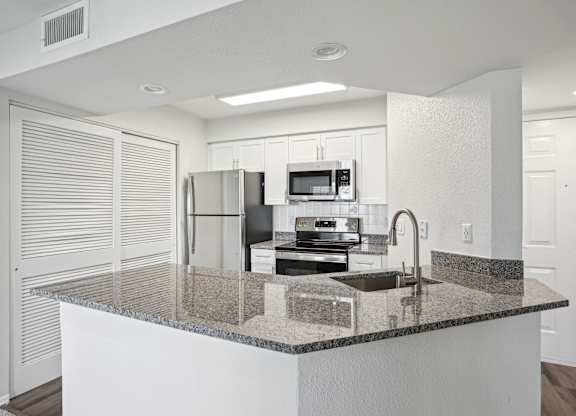 A kitchen with granite countertops and white cabinets.
