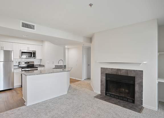 A white kitchen with a fireplace and a carpet.
