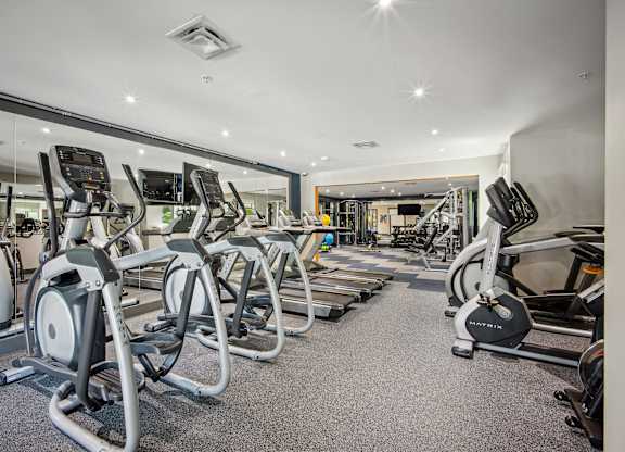 A gym with a variety of exercise equipment including treadmills, stationary bikes, and weight machines at Elme Bethesda, Bethesda, 20814