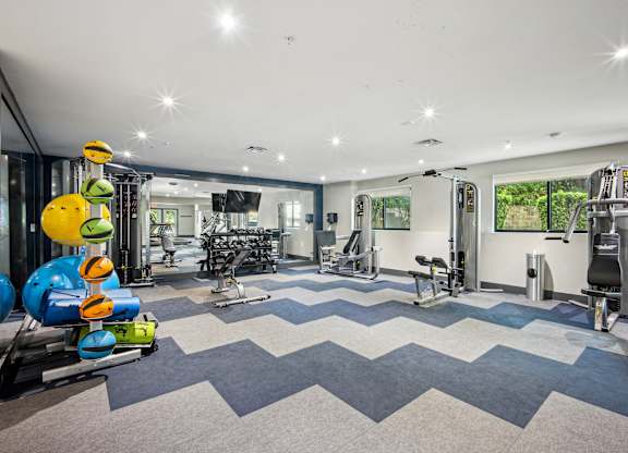 A gym with a variety of equipment including treadmills, weights, and exercise machines at Elme Bethesda, Bethesda, 20814